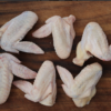 Raw Sommerlad heritage chicken wings arranged on a wooden board, six intact pieces.